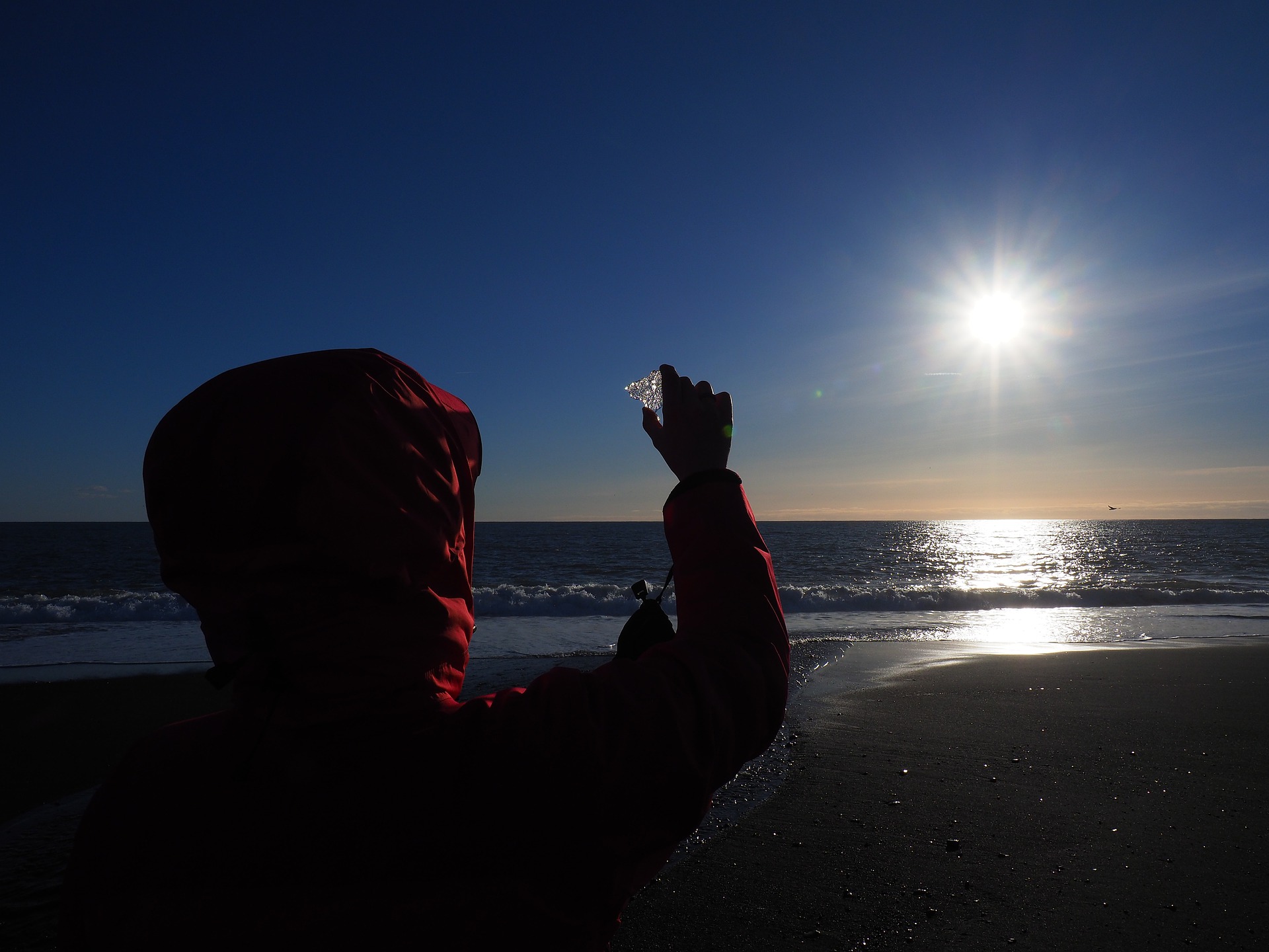 A person looking at the sunlight going through a piece of Ice in the hand at the Diamond Beach in Iceland