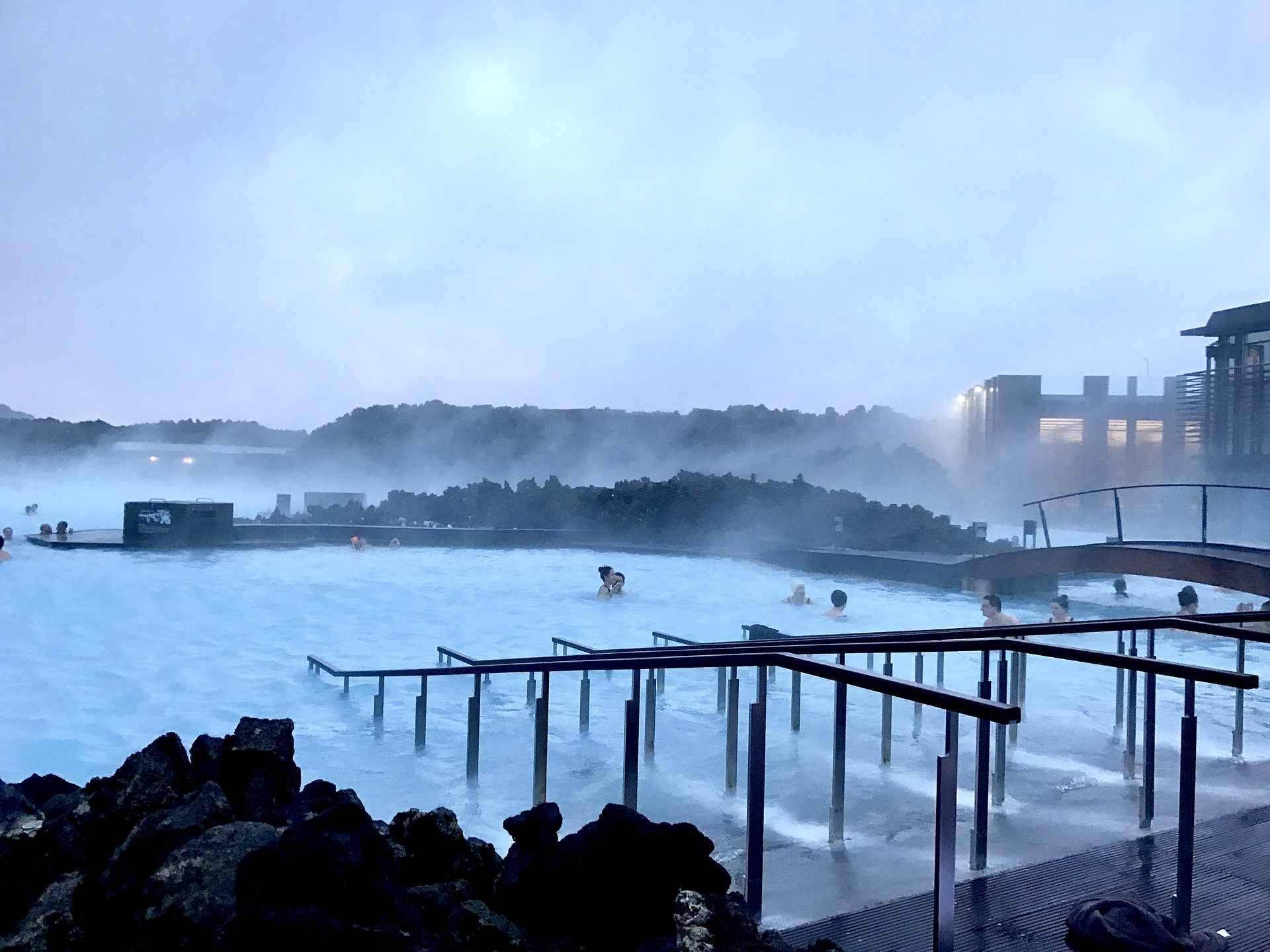 blue lagoon in iceland, with stairs to go to the lagoon, people are bathing in hot waters