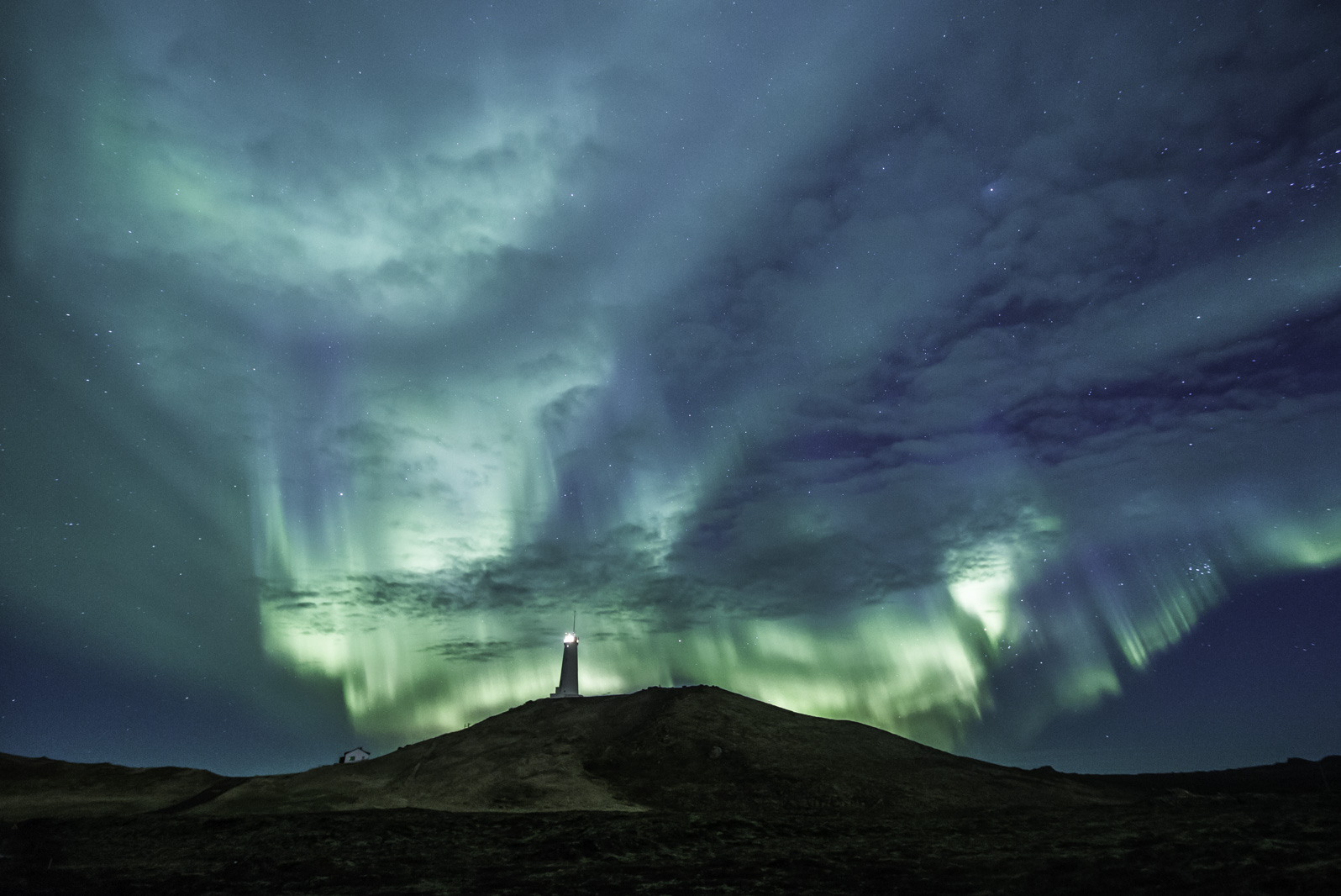 sky filled with blue and green northern lights in iceland