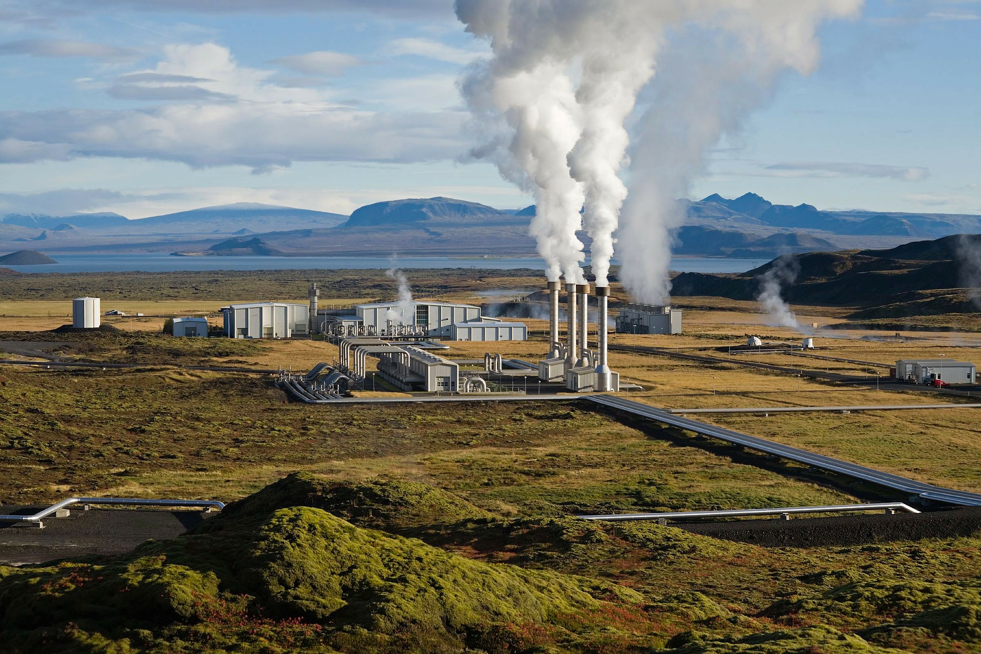 geothermal plant in Iceland, green plains, clear blue sky and mountains on the background