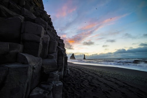 Reynisfjara beach iceland, black sand with basalt colums, blue sky, water and waves