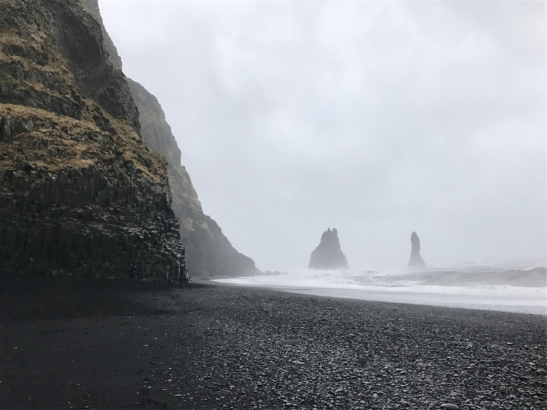 Reynisfjara Beach Iceland with fogg, basalt colums, sea stack, water and clouds