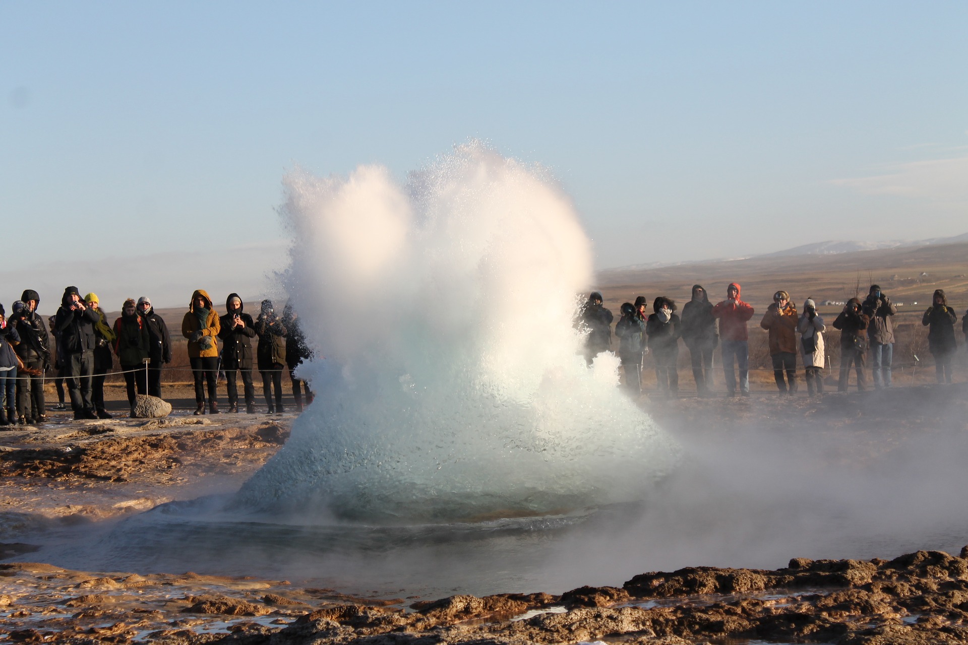 the start of a geyser at Geysir in Iceland, tourists on the background